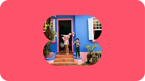 Family standing at the doorway of a blue house, framed in a B-shaped cutout on coral background