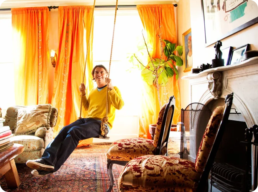 A homeowner relaxing on an indoor rope swing in a warm, sunlit room